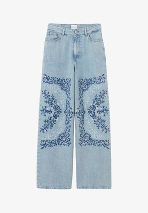 Vaqueros azul celeste de pierna ancha con bordado geométrico intrincado en azul oscuro y claro en los muslos y rodillas delanteros, estilo clásico de cinco bolsillos.