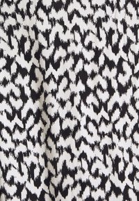 Svart och vit djurtryckstoff med oregelbundna, taggiga fläckar som bildar ett högkontrastmönster.