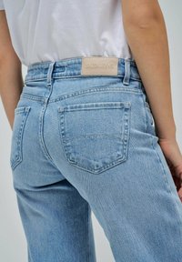 Jeans de mezclilla de color azul claro con corte recto. Las características incluyen dos bolsillos traseros y una etiqueta de cuero texturizado que dice "SALSA JEANS."