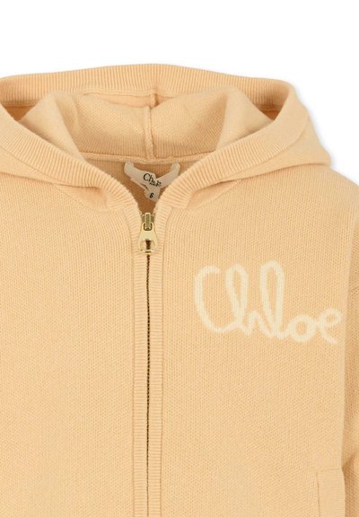 Beżowy dzianinowy hoodie na zamek z kapturem, na którym białym haftem na piersi wyszyto "Chloe".
