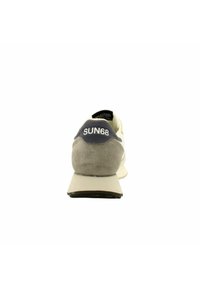 Chaussure de course pour homme avec un capuchon de talon en daim gris, un corps crème et une semelle en caoutchouc plate. Accentuée par le logo "SUN68" sur le talon.
