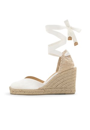 Espadrilla con zeppa bianca, suola intrecciata in juta, tallone intrecciato e lunghe nastri da annodare alla caviglia con un fiocco.