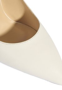 Escarpin en cuir blanc à bout pointu avec un design épuré, une texture lisse et des coutures discrètes le long des bords. L'intérieur comporte une doublure beige.