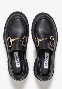 Czarne skórzane mokasyny z teksturowaną podeszwą, złotymi detalami i gładkim wykończeniem. Charakteryzują się okrągłym noskiem i niskim profilem.