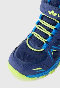 Baskets de sport bleues avec une tige en maille, des accents verts et bleus, des détails réfléchissants et des lacets élastiques. Comprend une sangle de cheville rembourrée.