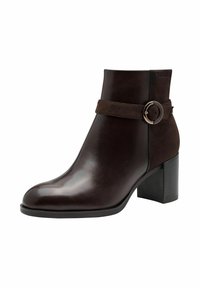 Bottine en cuir marron avec un bout rond, une sangle en suède et une boucle circulaire. Talon carré et finition lisse et brillante.