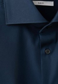 Granatowa koszula o dopasowanym kroju z gładką teksturą, wyposażona w spiczasty kołnierzyk i czarny guzik. Zawiera metkę z napisem "SLIM FIT".