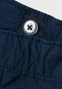 Cintura de tela azul marino con botones, que presenta un botón plateado brillante con un diseño de cuatro orificios, costuras detalladas y una textura suave.