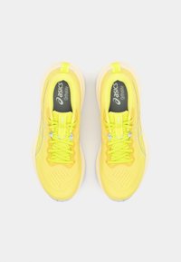 Baskets de sport jaunes éclatantes avec un dessus en maille respirante, un design à lacets et une semelle rembourrée. Comprend un logo sur la languette et des accents contrastants.