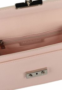Interno della borsa a mano rosa chiaro con pelle testurizzata, tasca con zipper e chiusura magnetica. Finitura liscia con dettagli hardware minimi.