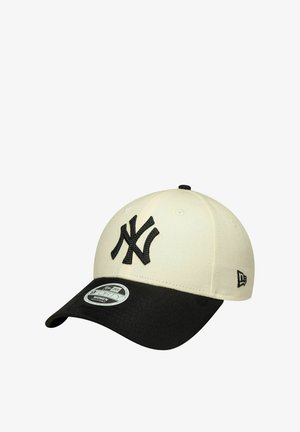 Gorra negra y crema con un logo bordado de los New York Yankees, una corona estructurada y una visera curvada con una textura sutil.