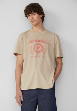 Beige Baumwoll-T-Shirt mit kurzen Ärmeln, das einen roten Grafikdruck und Text zeigt. Rundhalsausschnitt und lockere Passform.