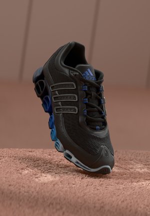 Juoda ir mėlyna Adidas sportinė batai su išskirtine kreiva padu, tinklelio ir sintetinės medžiagos viršumi, raišteliais ir Adidas logotipu ant liežuvio, ant tekstūruoto paviršiaus.