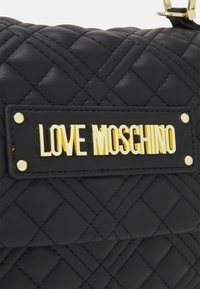 Svart quiltad fusk läder väska med en guld-tonad "LOVE MOSCHINO" logoplack och guld hardware detaljer. Texturerat mönster med sydda detaljer.