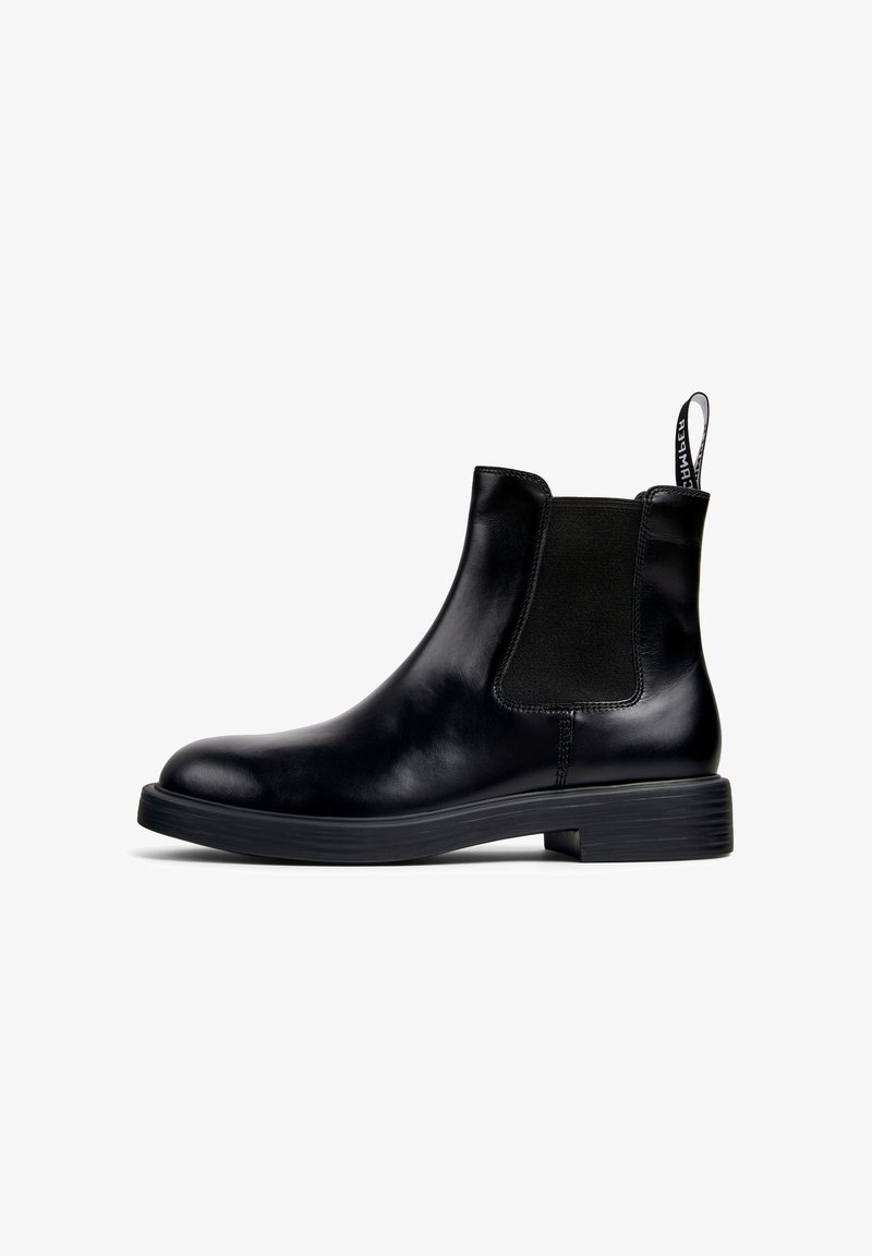 Black leather Chelsea ankle boot with elastic side panel, low heel, and pull tab with white text on a white background.