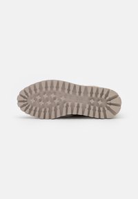Semelle de chaussure en caoutchouc beige clair avec des motifs profonds, des arêtes et des motifs en forme d'étoile pour une meilleure adhérence. Texture lisse, construction durable.