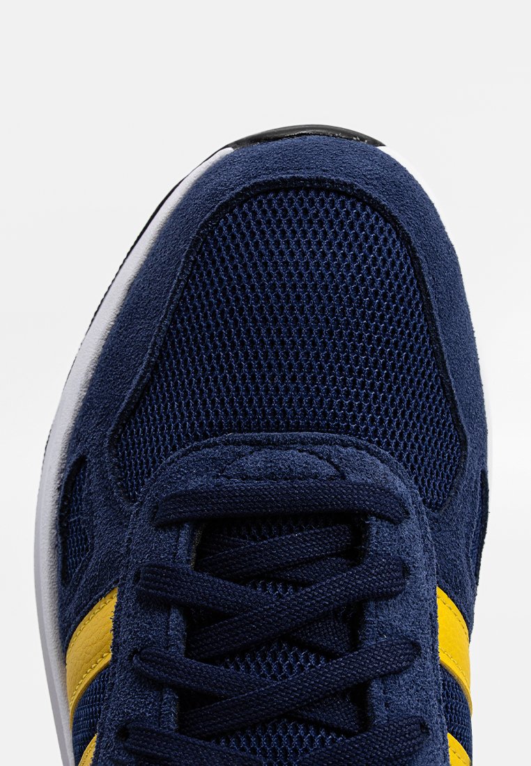 Granatowe trampki z siateczkowej cholewki, z zamszowymi akcentami, żółtymi paskami oraz teksturowanym systemem sznurowania, na białej podeszwie.