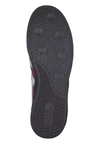 Semelle de chaussure en caoutchouc noir avec des grips circulaires et des motifs texturés, présentant un design ondulé et un détail de logo près du centre.
