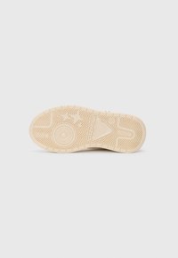 Beige sneakerzool met patronen zoals concentrische cirkels, sterren en de merknaam "PRIMIGI" in reliëf op een plain witte achtergrond.