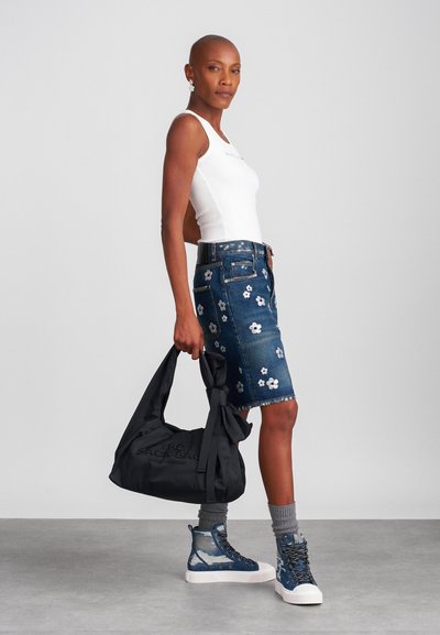Denim seelik valgete lillede tikandiga, mille juurde on sobitatud valge kampsun ja must kott. Sinised kõrged tenniseketid koos kudumissokkidega.
