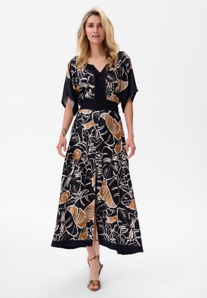 Robe noire longue avec des motifs de feuilles tropicales en beige et blanc, dotée d'un décolleté en V, de manches larges et d'une taille cintrée.
