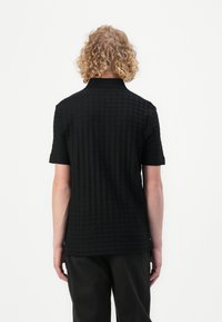 Svart polo skjorte med et teksturert diamantmønster, korte ermer og klassisk krage. Bakvisning viser en skreddersydd passform og glatt stoff.