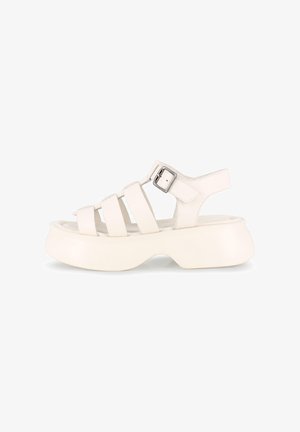 Sandalias de cuero blanco con una suela de plataforma gruesa, que presentan múltiples correas delgadas y un buckle lateral para ajuste. Textura suave.
