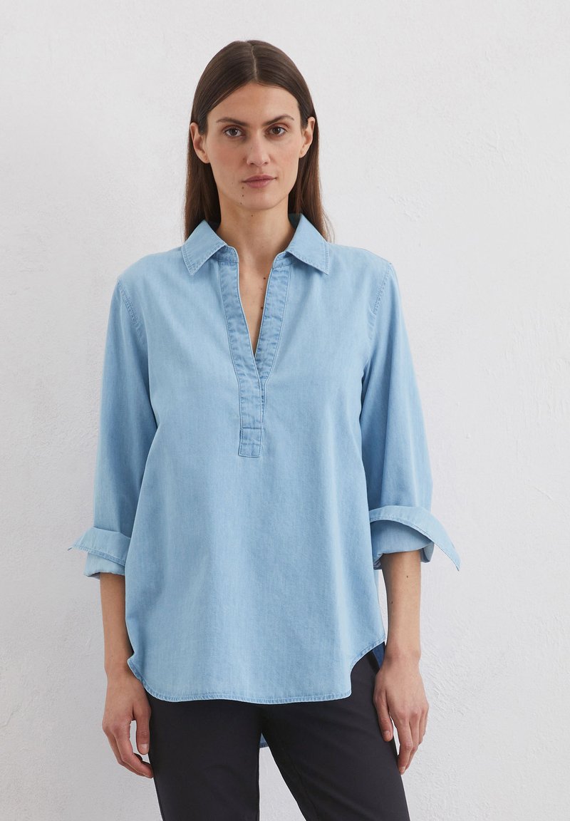 Lichtblauwe denim overhemd met een kraag, knoopsluiting en 3/4 mouwen. Heeft opgerolde mouwen en een ronde zoom. Soepele textuur.
