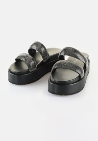 Svarta plattformssandaler med två breda, metalliska silverremmar. Slät, matt svart innersula och texturerad gummiyttersula för bra grepp.