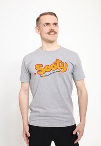 Grå bomulds t-shirt med "Sooty" logo i fed gul og rød, med blå tekst og røde stjerner. Kortærmet og med rund halsdesign.