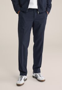 Marinrandiga byxor i ett mjukt tyg med rak skärning, har sidofickor och gylf, kombinerat med vita sneakers.