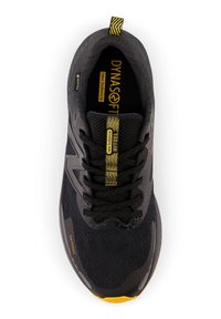 Zapatilla de correr negra con parte superior de malla, acentos amarillos y refuerzo en la puntera. Presenta amortiguación Dynasoft y un sistema de cordones con patrón.