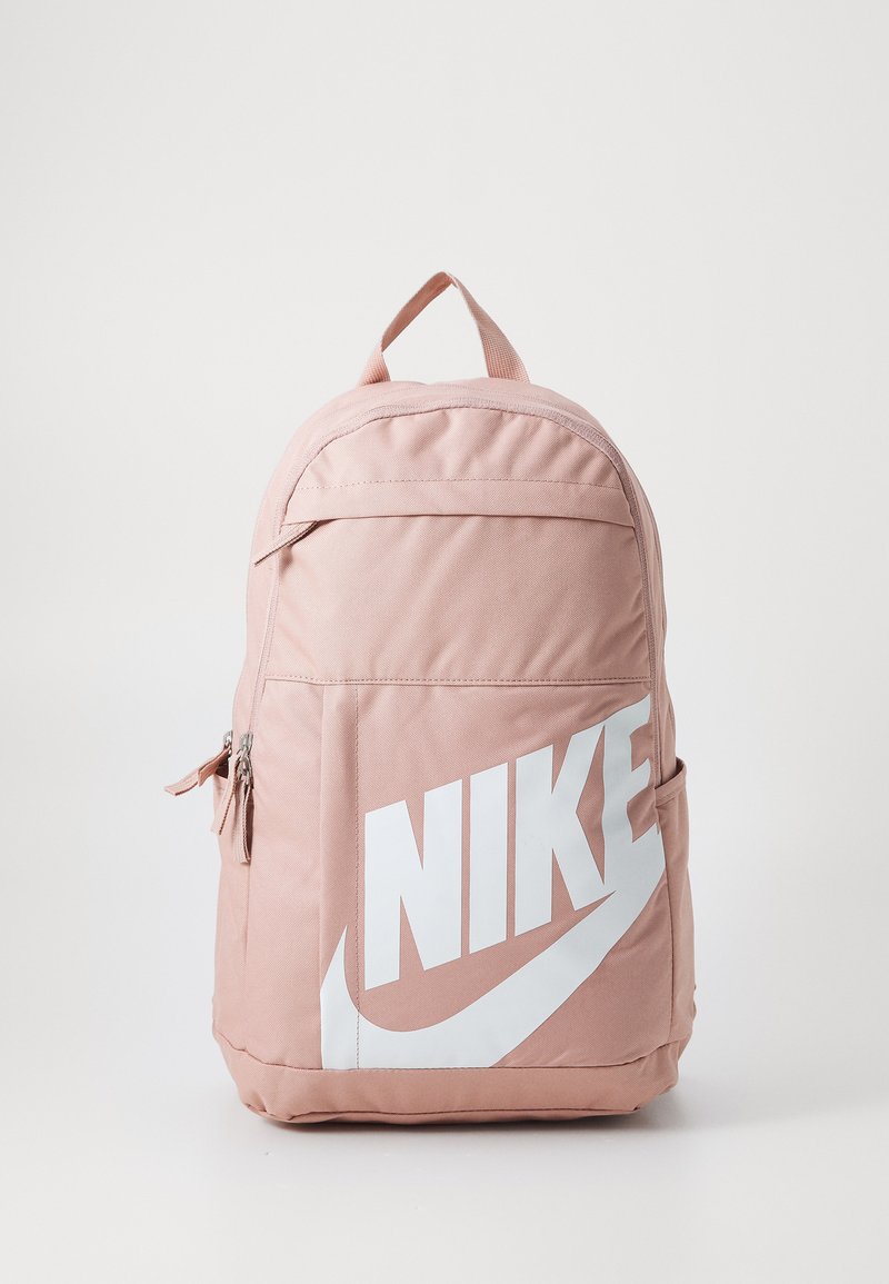 Růžový látkový batoh s kulatým vrchem, velkým bílým logem Nike, boční kapsou se zipem a nastavitelnými ramenními popruhy. Hladký povrch, pevná konstrukce.