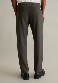 Gray wool trousers with a relaxed fit, elastic waistband, and two rear pockets, paired with black footwear.