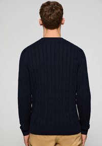 Navy Kabelstrickpullover mit Rundhalsausschnitt und gerippten Bündchen und Saum. Hergestellt aus einem strukturierten Strickstoff, hat er eine taillierte Passform.
