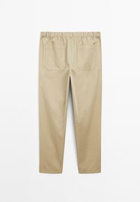 Beige, elastic waist pants made of cotton blend, featuring two back pockets with a square design. Smooth texture and tapered shape.
