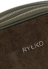 Rjav usnjen paketek s podrobnostmi iz srebrne zlitine in blagovno znamko "RYŁKO" v kovinskem tisku na teksturirani površini.