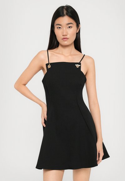 Robe mini noire avec des bretelles fines, décolleté carré et accents dorés sur les bretelles. Fabriquée en tissu lisse, avec une jupe évasée.