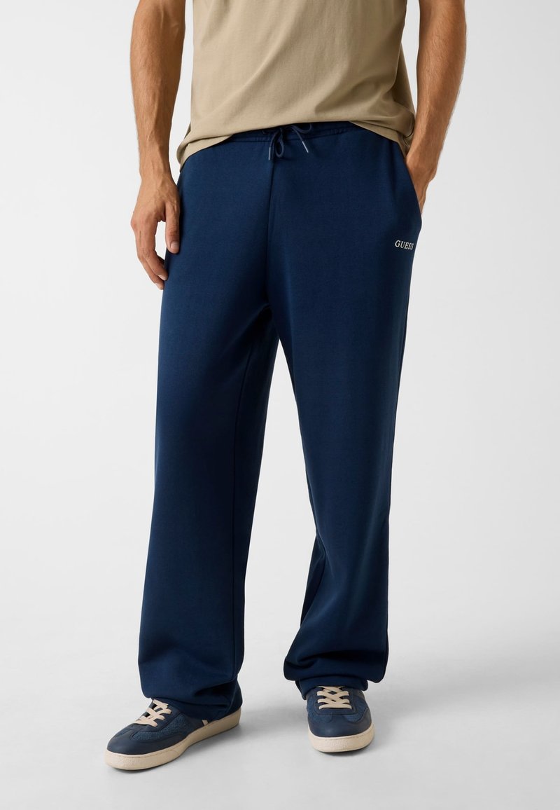 Marineblaue Jogginghose aus weichem Stoff mit lockerem Schnitt. Verfügt über einen Kordelzug an der Taille und ein kleines Logodetail am rechten Bein.