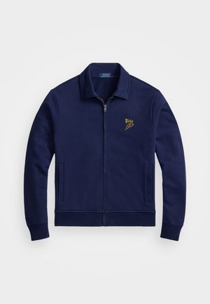 Marineblauwe ritsjack gemaakt van zachte stof, met een kraag, twee zijzakken en een goud geborduurd logo op de bovenste linkerborst.