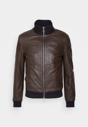 Brązowa skórzana kurtka bombowa zapinana na zamek błyskawiczny, z czarnym ściągaczem przy kołnierzu i mankietach. Charakteryzuje się gładką fakturą i dopasowanym krojem.