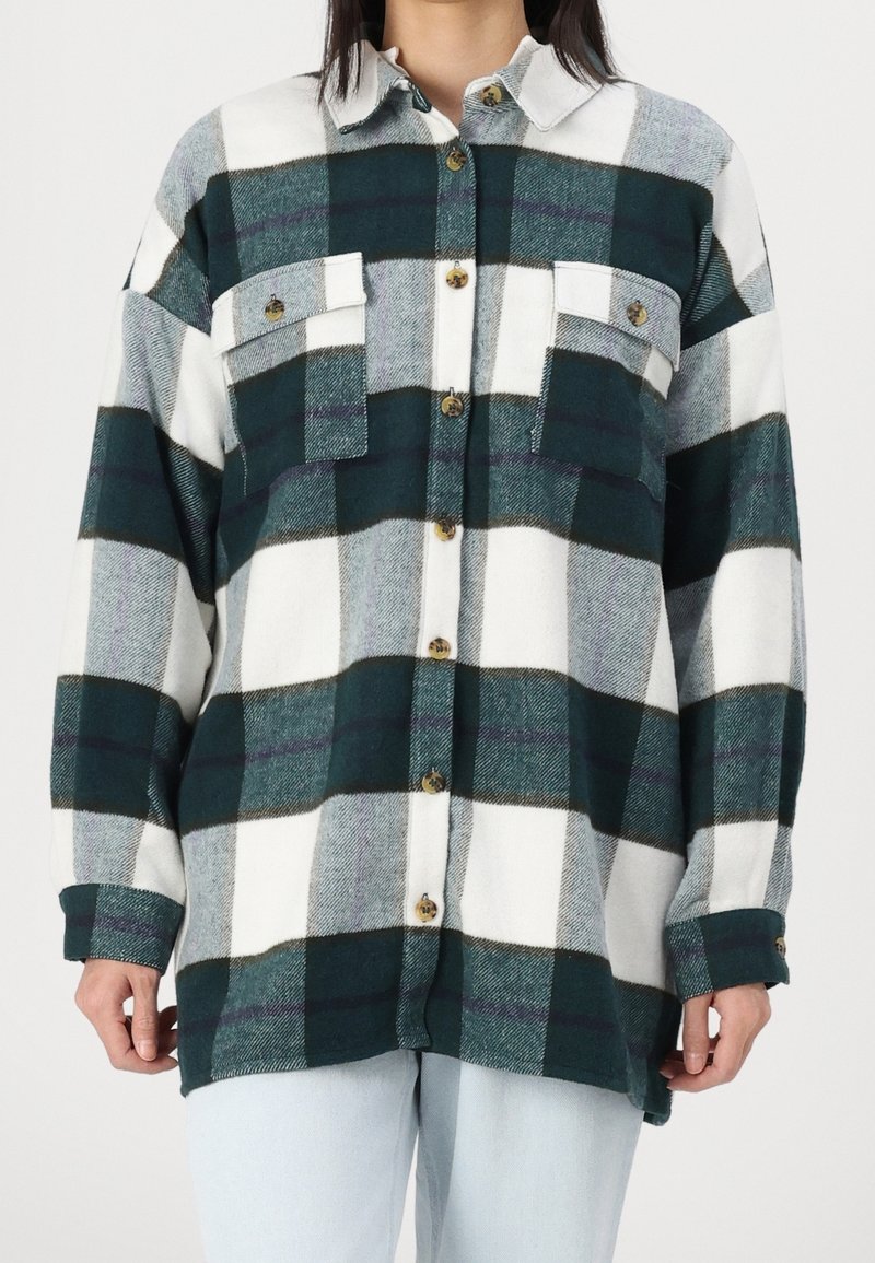 Zielono-biała flanelowa koszula w kratę z dwoma kieszeniami na piersi, zapinana na guziki, z długimi rękawami. Miękka w dotyku, o luźnym kroju.