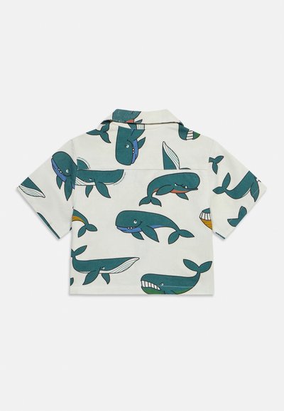Λευκό πουκάμισο με κοντά μανίκια, με τυρκουάζ καρτούν φάλαινες τυπωμένες παντού, με διάφορα παιχνιδιάρικα και χαμογελαστά σχέδια φαλαινών.