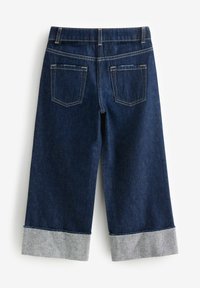 I culottes in denim scuro presentano un design a gamba larga e cropped con un risvolto grigio chiaro. Le tasche posteriori e le cuciture a contrasto offrono dettagli ben evident. 