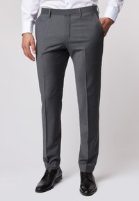 Graue, maßgeschneiderte Hosen mit glatter Textur, geradem Schnitt, Bundfalten und seitlichen Taschen, kombiniert mit schwarzen Lederschuhen.