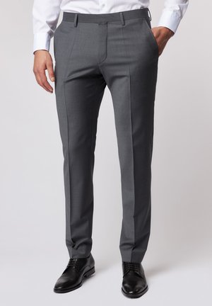 Grey tailored trousers with a smooth texture, featuring a straight cut, front pleats, and side pockets, paired with black leather shoes.