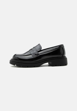 Mocassin en cuir noir brillant avec semelle épaisse à crampons et bride penny, présenté en profil latéral sur fond blanc uni.