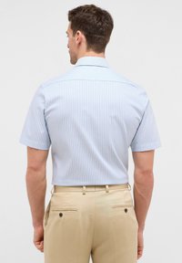 Korte mouwen shirt met lichtblauwe en witte verticale strepen, met een standaardkraag en gladde katoen, gedragen met beige broeken.