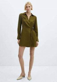 Olive green, collared dress with long sleeves and a wrap design, featuring a tie at the waist and a textured fabric.