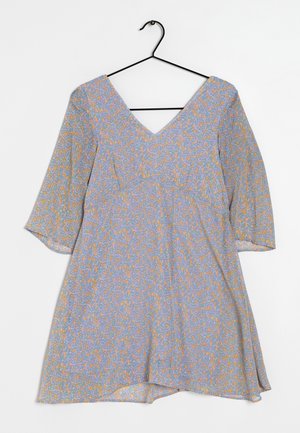 Vestito con motivo floreale in azzurro chiaro con elementi arancioni e verdi, presenta una scollatura a V, maniche a tre quarti e una gonna fluida. Appeso a un gancio nero.